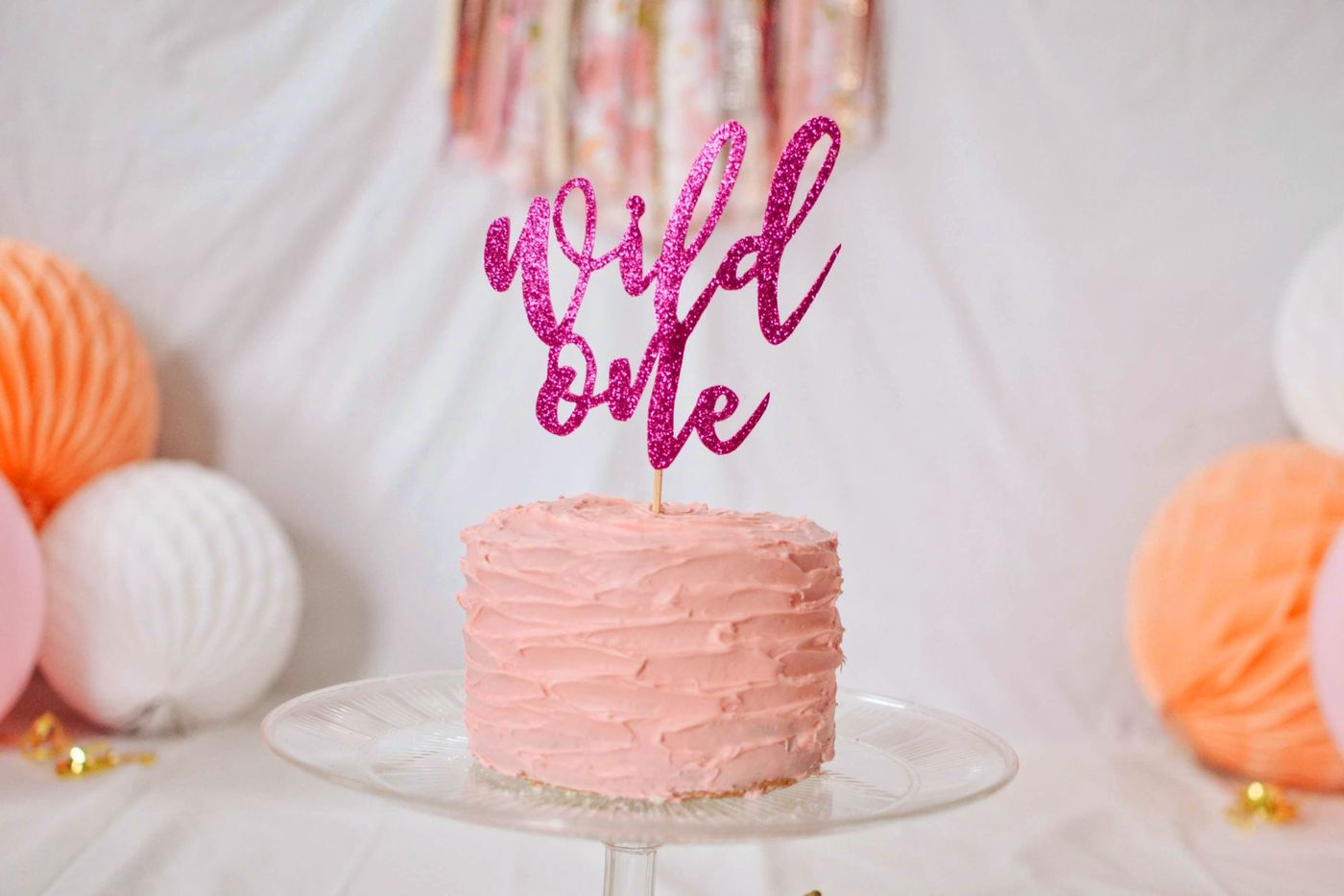 A pink buttercream cake with a hot pink glitter cake topper